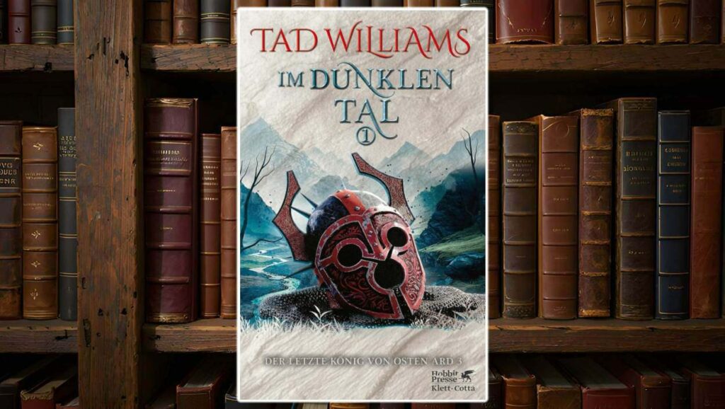 Buchcover von Im dunklen Tal (Der letzte König von Osten Ard 3) von Tad Williams: Ein stilisierter, rot verzierter Kriegshelm liegt auf einem Kettenhemd in einer düsteren, bergigen Landschaft. Der Titel ist in blauer Schmuckschrift auf hellem Pergamenthintergrund gesetzt, der Autorenname sticht in kräftigem Rot hervor. Verlag: Hobbit Presse Klett-Cotta.