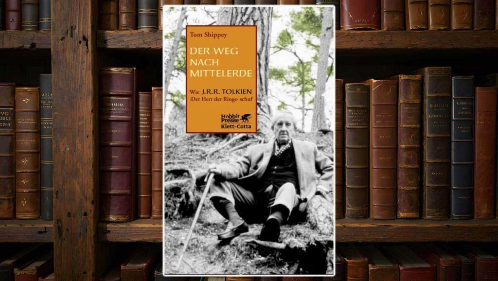 Buchcover von Der Weg nach Mittelerde von Tom Shippey: Schwarz-weiß-Foto von J. R. R. Tolkien, wie er mit Spazierstock an einen Baum gelehnt im Wald sitzt. Links oben ein orangefarbenes Textfeld mit Titel und Unterzeile: ‚Wie J. R. R. Tolkien Der Herr der Ringe schuf‘. Verlag: Hobbit Presse Klett-Cotta.