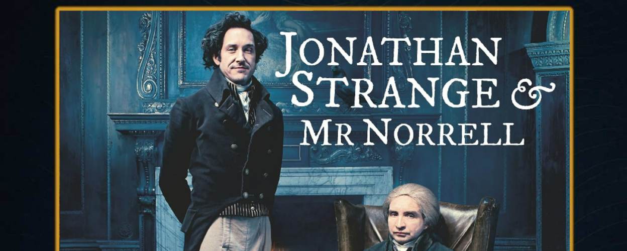 Cover des Hörbuchs „Jonathan Strange & Mr Norrell“ von Susanna Clarke. Zwei Herren im Stil des frühen 19. Jahrhunderts posieren in einem elegant-dunklen Salon: Jonathan Strange steht links im Gehrock, Mr Norrell sitzt rechts in einem Sessel vor einem Kamin. Der Raum ist edel eingerichtet, mit Teppich, Kerzen, Silbertablett und klassischer Wandvertäfelung. Der Titel steht in weißer Serifenschrift oben rechts.