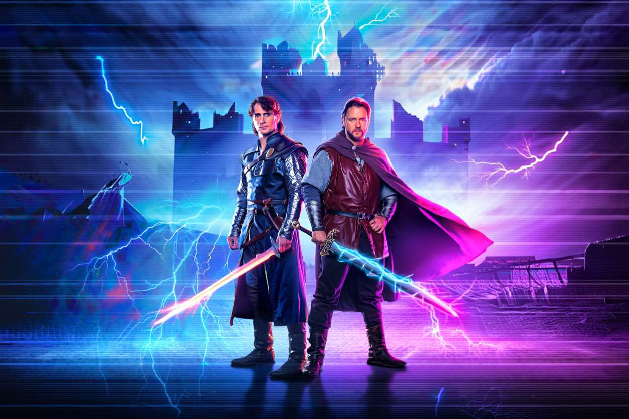 Zwei Männer im Blitzgewitter, die aussehen wie Henry Cavill und Russell Crowe im Laserschwert-Urlaub – vor Retro-Schlossruinen, mit Strom im Umhang und VHS-Stil im Herzen. Wenn Highlander bei Tron übernachtet hätte.