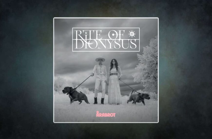 Albumcover Årabrot – Rite Of Dionysus: Schwarz-weiß Fotografie, Kjetil Nernes im Cowboy-Outfit mit Hut und Karin Park im weißen Kleid führen zwei bullige Hunde an Leinen. Surreale, kontrastreiche Landschaft mit wolkigem Himmel, darüber Albumtitel in geometrischer Typografie.