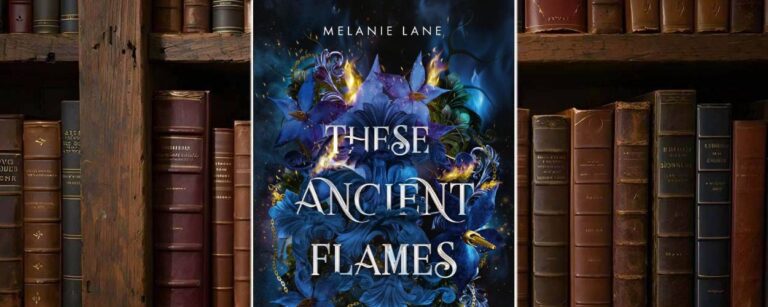 Cover von These Ancient Flames 1: Awake von Melanie Lane: Üppiges, dunkles Fantasy-Cover mit blauen Lilien, goldenen Flammenakzenten und filigranen Ornamenten. Titel in Silberprägung, unten Hinweis „mit verstecktem Farbschnitt“.