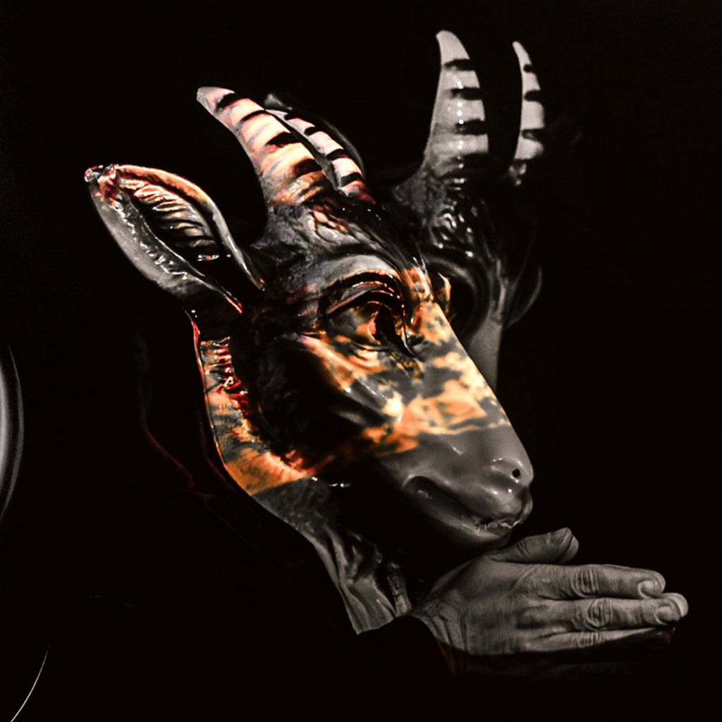 AAlbumcover von „Occult Pleasures“ (2025) der österreichischen Ritual-Darkwave-Band The Devil & The Universe: zwei schwarze Ziegenmasken, ineinander verschränkt, mit Flammenprojektionen und gefalteten Händen – okkulte Symbolik zwischen Ritual und Performance.