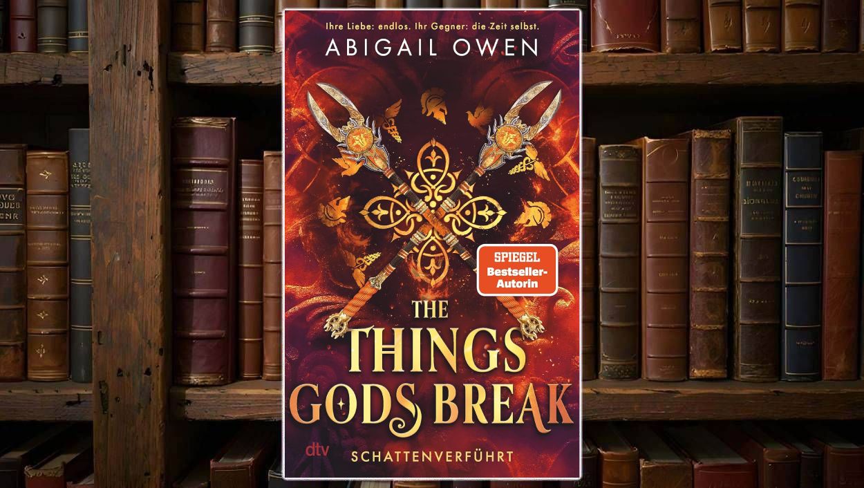 Cover von Abigail Owens »The Things Gods Break – Schattenverführt« vor einem Bücherregal: Auf feurig rotem Hintergrund kreuzen sich vier reich verzierte Speere um ein goldenes Ornament, darum schweben kleine mythische Symbole. Oben stehen der Autorenname und der Claim „Ihre Liebe: endlos. Ihr Gegner: die Zeit selbst“, unten prangt der Titel in großen goldenen Lettern mit dem Untertitel „Schattenverführt“ und einem orangefarbenen SPIEGEL-Bestseller-Sticker.