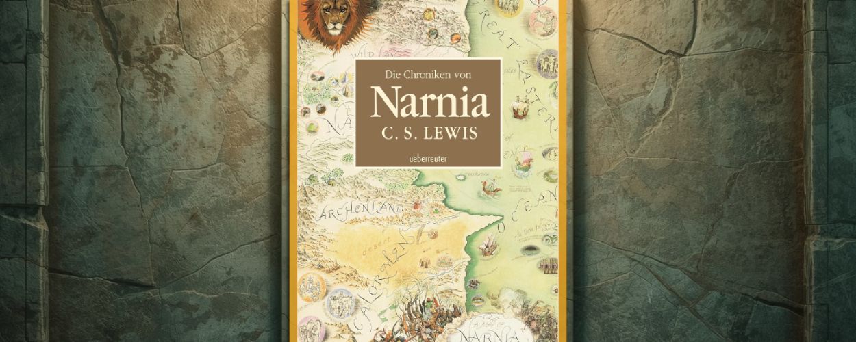 Cover der Ueberreuter Gesamtausgabe von Die Chroniken von Narnia von C. S. Lewis, mit gezeichneter Karte Narnias, Löwenkopf in der Ecke und dekorativem Rahmen wie ein gerahmtes Bild an einer steinernen Wand.