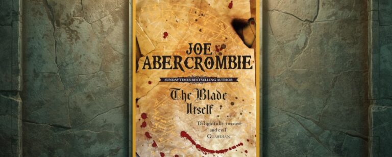 Vor einer rissigen, moosig wirkenden Steinwand hängt das Cover von Joe Abercrombies The Blade Itself in einem goldenen Rahmen. Die Gestaltung zeigt Pergamentoptik, feine Linien wie eine Karte und rote Blutspritzer, wodurch das Motiv wie ein ausgestelltes Relikt wirkt.