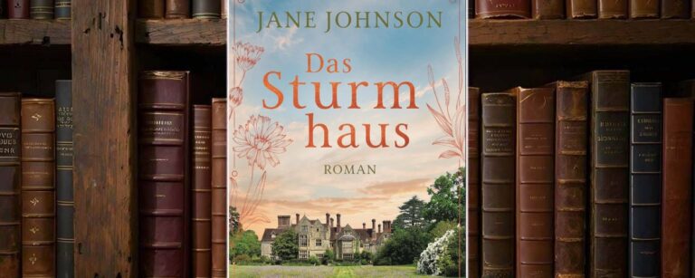 Buchcover von „Das Sturmhaus“ vor einem Regal mit alten Ledereinbänden: In der Mitte sieht man ein großes, herrschaftliches Landhaus im englischen Stil, umgeben von grünen Bäumen und einer weitläufigen Wiese mit lilafarbenen Blumen. Ein gerader Grasweg führt auf das Haus zu. Am Himmel liegt ein weiches Abendlicht mit blau-orangem Farb