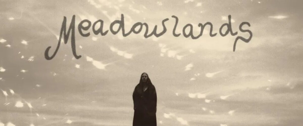 Albumcover von Moon Mother – »Meadowlands«: schwarzweißes Foto einer einsamen Gestalt auf einem Hügel unter dramatischem Himmel, darüber der handgeschriebene Schriftzug Meadowlands
