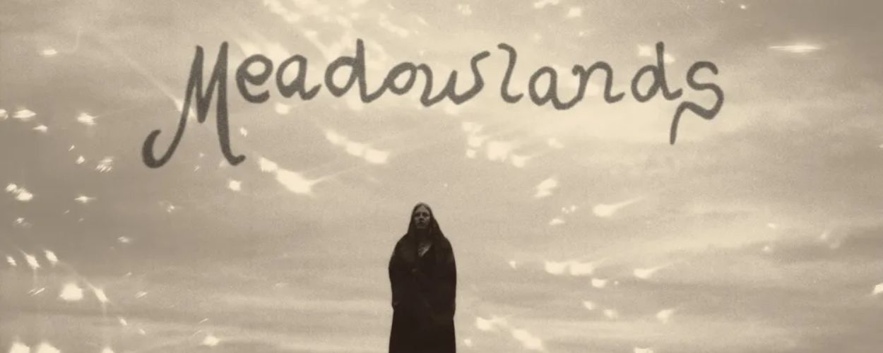 Albumcover von Moon Mother – »Meadowlands«: schwarzweißes Foto einer einsamen Gestalt auf einem Hügel unter dramatischem Himmel, darüber der handgeschriebene Schriftzug Meadowlands