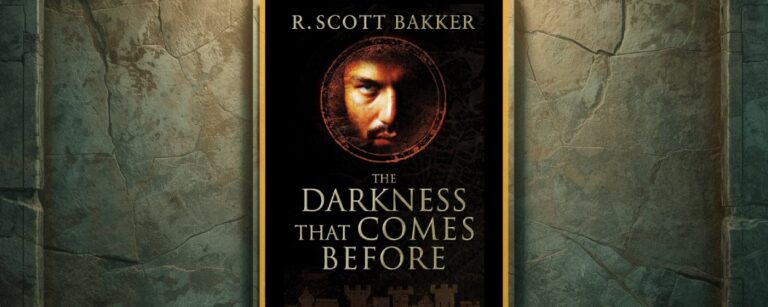 Buchcover von „The Darkness That Comes Before“ von R. Scott Bakker im goldenen Rahmen vor einer verwitterten Steinwand; im Zentrum ein düsteres Gesicht im Kreis aus Symbolen.