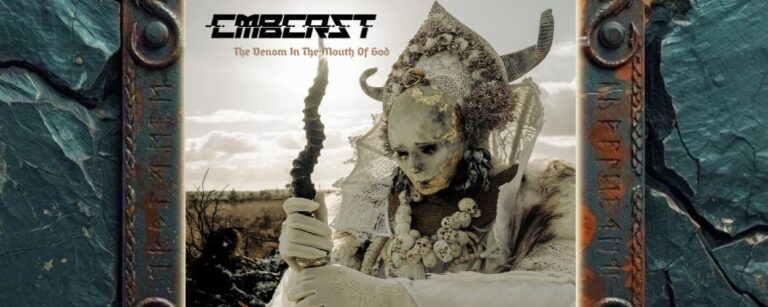 Albumcover von Combichrist – The Venom In The Mouth Of God: Eine bleiche, reich verzierte Gestalt mit hörnerbesetzter Kopfbedeckung, Schädelketten und weißem Gewand hält in einer kargen Landschaft einen dunklen Stab. Ihr Gesicht ist teilweise von goldenen Rissen und dunklen Spuren überzogen. Oben links stehen Bandlogo und Albumtitel.