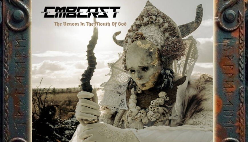 Albumcover von Combichrist – The Venom In The Mouth Of God: Eine bleiche, reich verzierte Gestalt mit hörnerbesetzter Kopfbedeckung, Schädelketten und weißem Gewand hält in einer kargen Landschaft einen dunklen Stab. Ihr Gesicht ist teilweise von goldenen Rissen und dunklen Spuren überzogen. Oben links stehen Bandlogo und Albumtitel.