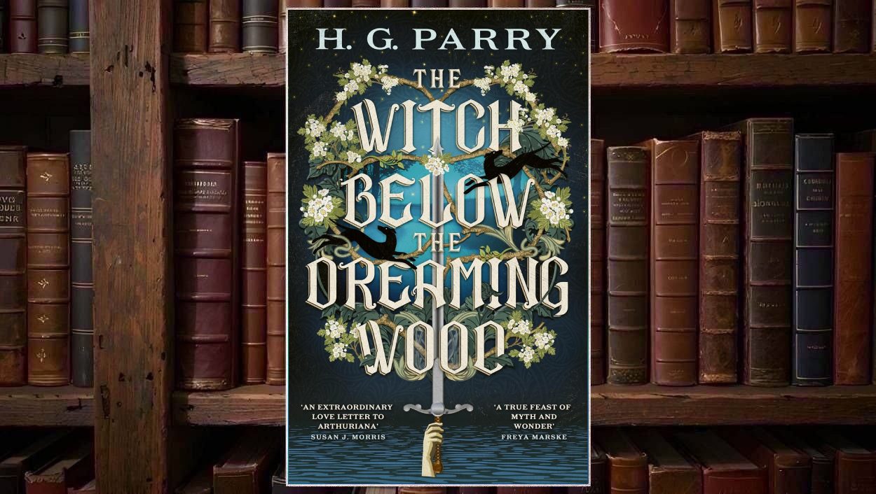 Cover von H. G. Parrys The Witch Below the Dreaming Wood mit einem senkrechten silbernen Schwert, weißen Blütenzweigen, schwarzen Vögeln und ornamentalen Blättern vor einem dunkelblauen Wald- und Wassermotiv.