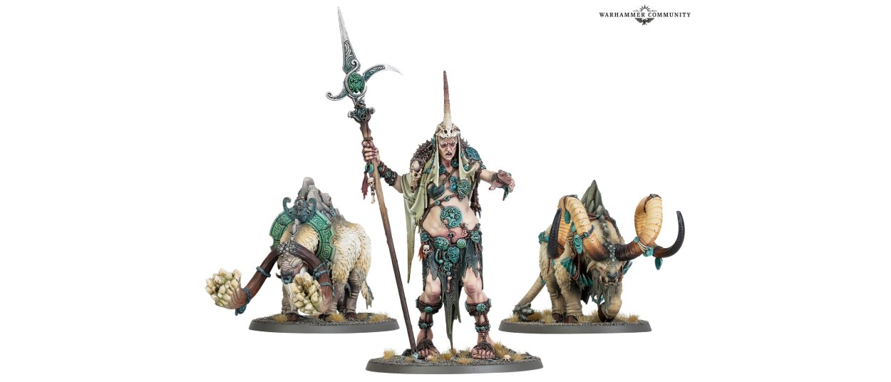Ma Maegran steht als bemalte Gargant-Miniatur mit langem Stab zwischen zwei massigen gehörnten Ghyroch-Kreaturen auf weißen Hintergrund.