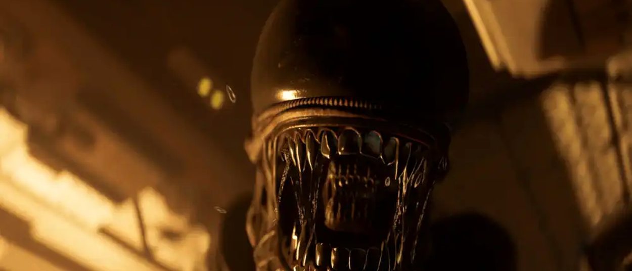Ein Xenomorph mit geöffnetem Maul nähert sich in einem dunkel orange beleuchteten industriellen Korridor unmittelbar dem Betrachter.