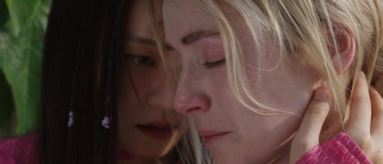 Sarah Bolger hält sich als Sarah ein Ohr zu, während Ko Asung als Eunbyeol dicht hinter ihr steht.