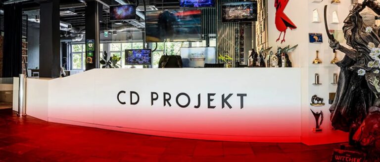 Der Empfangsbereich eines Spieleentwicklers mit großem CD-PROJEKT-Schriftzug, rotem Boden, Bildschirmen und einer Fantasyfigur am rechten Bildrand.