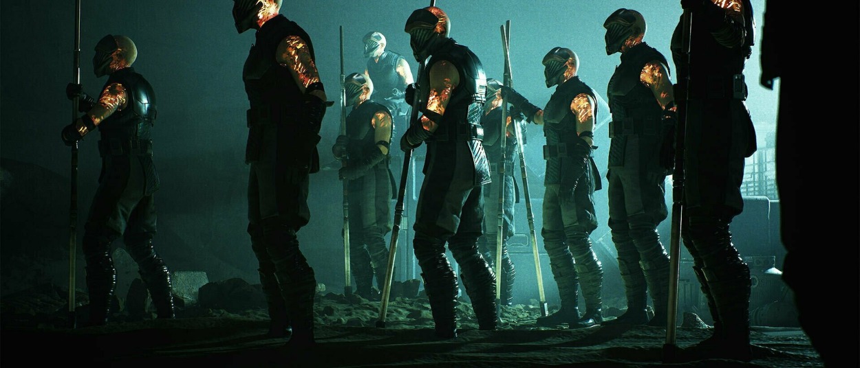 Mehrere vermummte Kämpfer des Infinite Coil stehen mit langen Waffen in einer dunklen Halle und werden von kaltem grünblauem Licht beleuchtet.