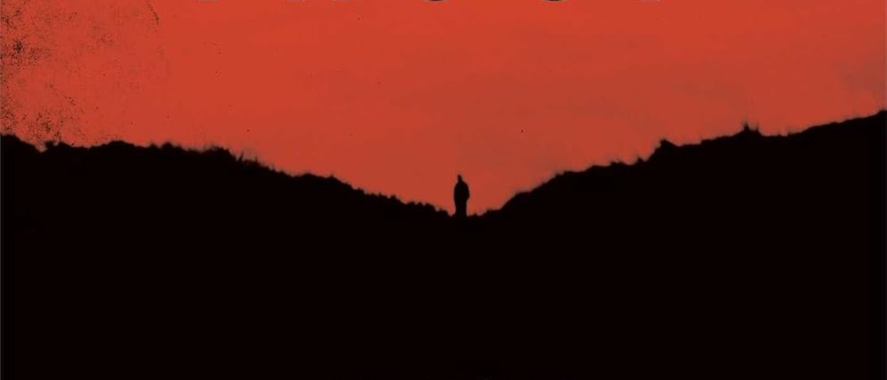 Eine einzelne menschliche Silhouette steht zwischen dunklen bewaldeten Hügeln unter einem intensiv rot gefärbten Himmel.