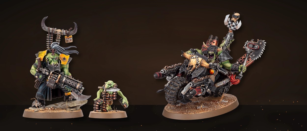 Links steht ein schwer bewaffneter grüner Ork mit großer Schusswaffe neben einem kleinen Grot. Rechts rast ein Ork auf einem massiven schwarzen Warbike mit mehreren Geschützen durch eine dunkle rostfarbene Umgebung.