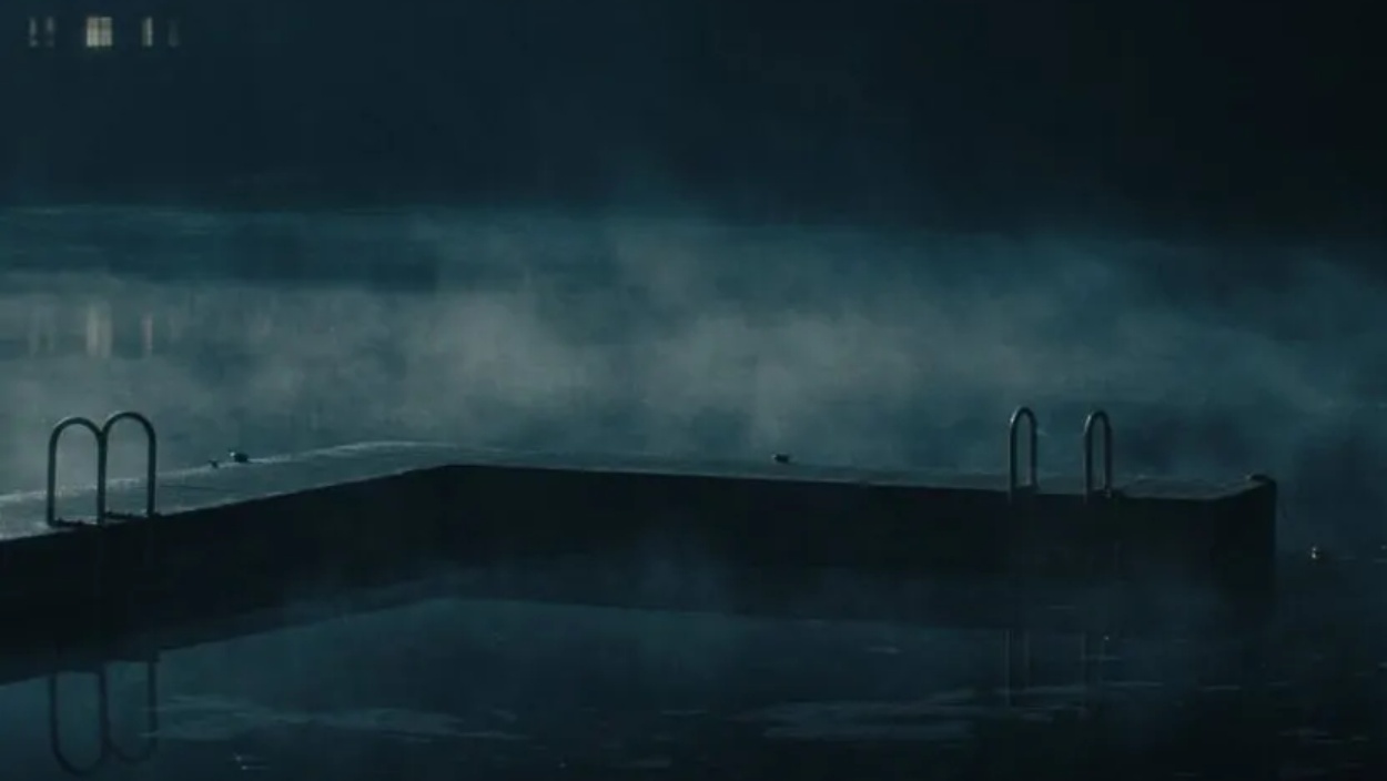 Ein leerer Bootssteg ragt nachts in den nebligen Crystal Lake, während das Wasser dunkel und nahezu regungslos wirkt.