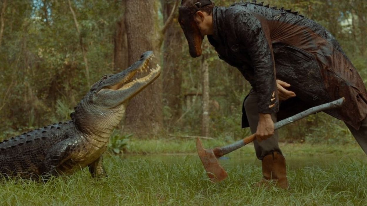 Ein Mann mit Axt steht in einer sumpfigen Waldlandschaft einem großen Alligator gegenüber.