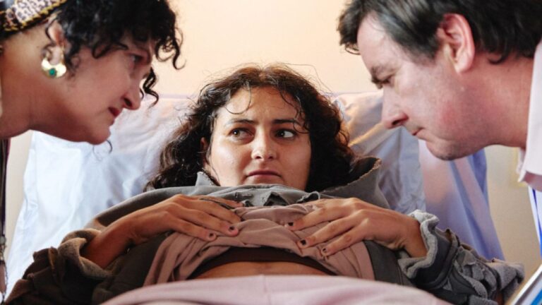 Mary liegt schwanger in einem Krankenhausbett, während ihre Mutter und ein Arzt sie im Science-Fiction-Horrorfilm Mum, I’m Alien Pregnant untersuchen.
