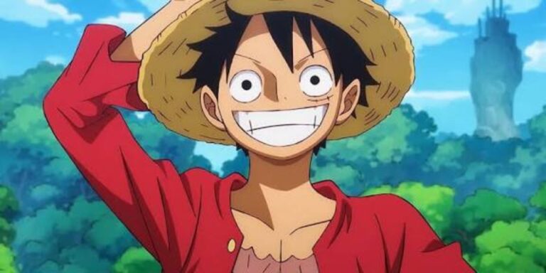 Luffy aus One Piece grinst breit unter seinem Strohhut vor einer grünen Landschaft und blauem Himmel.