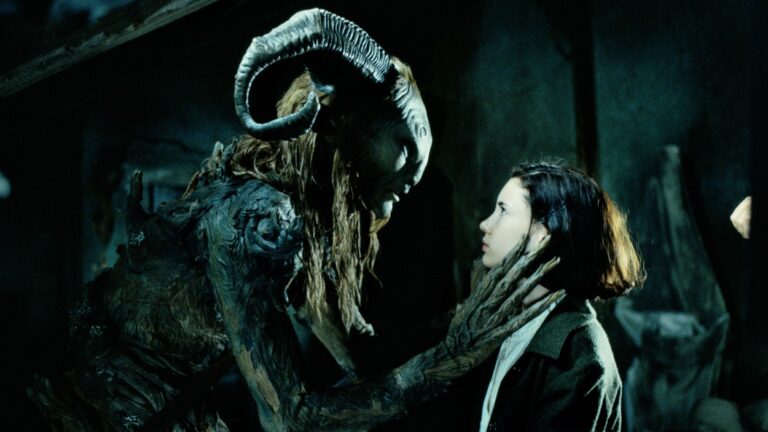Ofelia steht dem gehörnten Faun aus Pans Labyrinth in einer dunklen, märchenhaften Umgebung gegenüber, während er ihr mit langen Händen das Gesicht berührt.