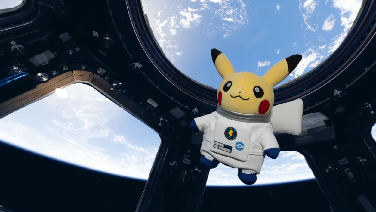 Ein Pikachu-Plüschtier im weißen Astronautenanzug schwebt vor den Fenstern der Internationalen Raumstation, während im Hintergrund die Erde zu sehen ist.