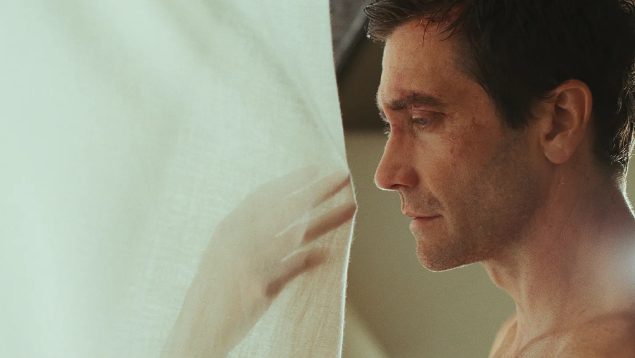 Jake Gyllenhaal steht im Profil vor einer hellen, schemenhaften Gestalt beziehungsweise Spiegelung hinter einem Vorhang.