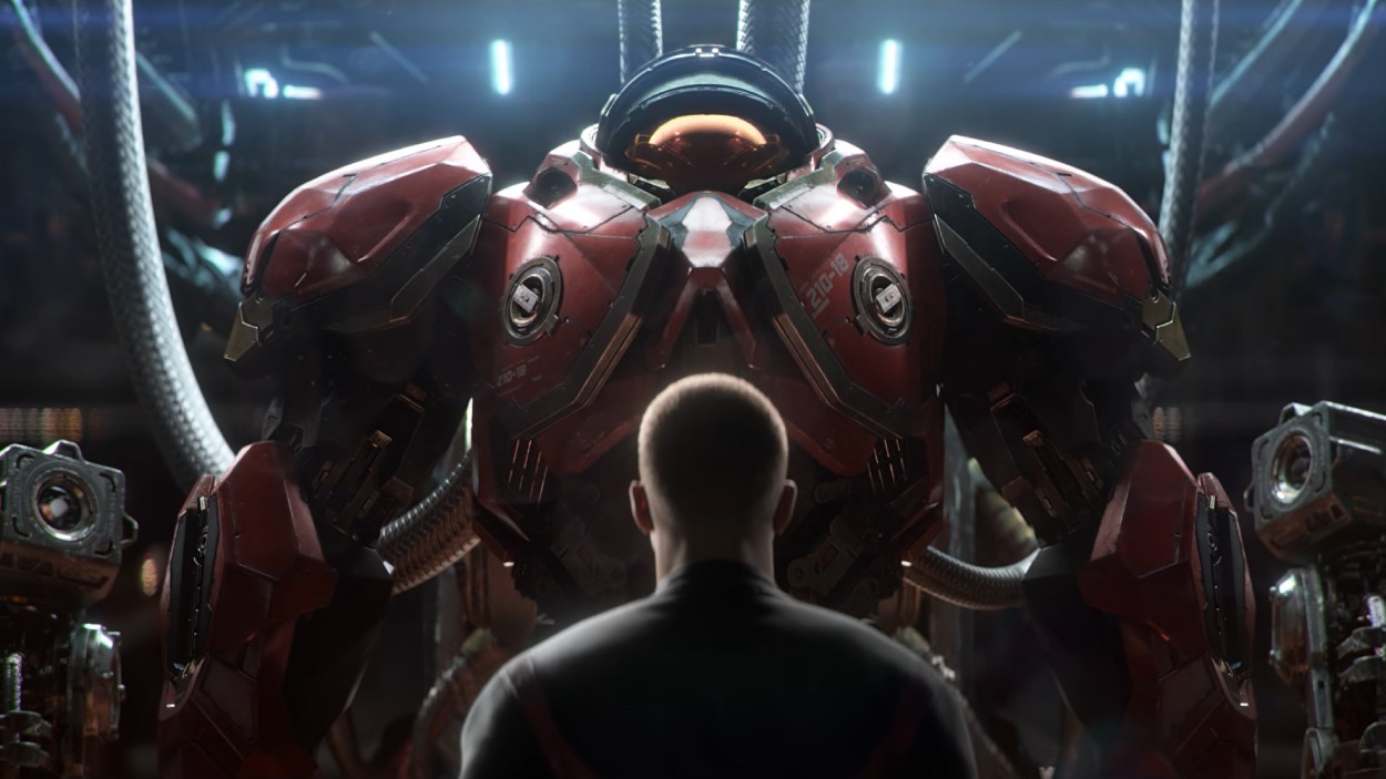 Ein Mann steht in einem futuristischen Hangar vor einer gewaltigen roten Terran-Kampfrüstung aus dem neuen StarCraft.