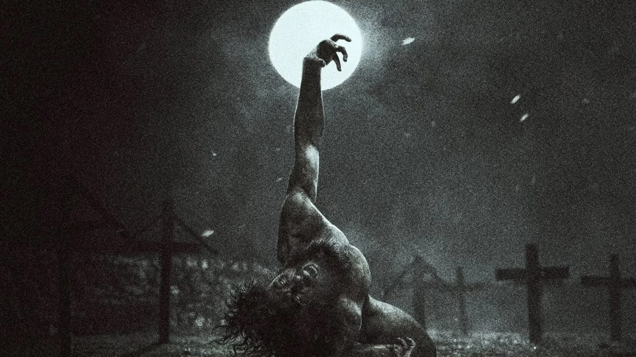 Eine verzerrt am Boden liegende Gestalt streckt unter einem hellen Vollmond einen Arm nach oben; die grobkörnige Schwarzweißaufnahme wirkt roh und bedrohlich.