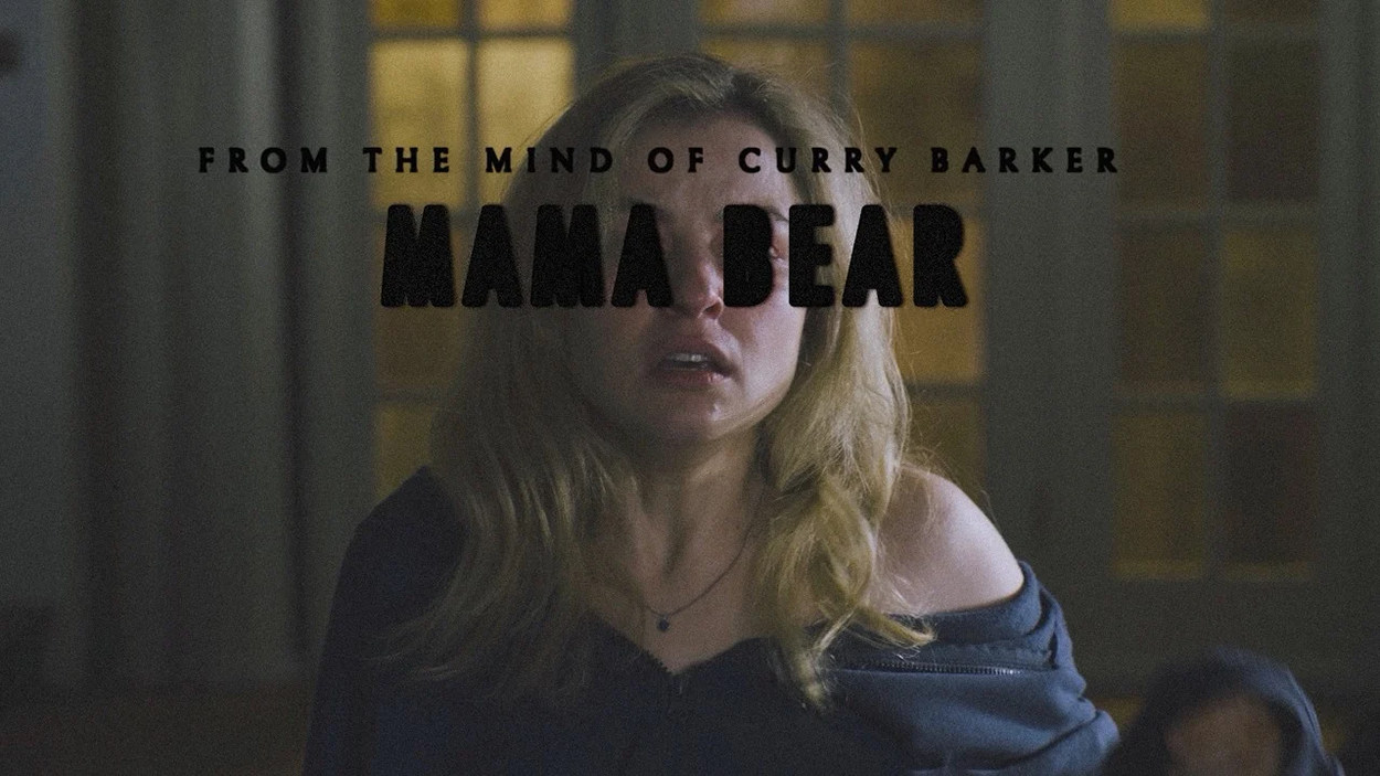 Promobild zu Mama Bear: Eine verängstigte blonde Frau steht in einem dämmrigen Raum vor einem Fenster. Über dem Bild liegt der schwarze Titel „Mama Bear“ sowie der Hinweis „From the Mind of Curry Barker“.