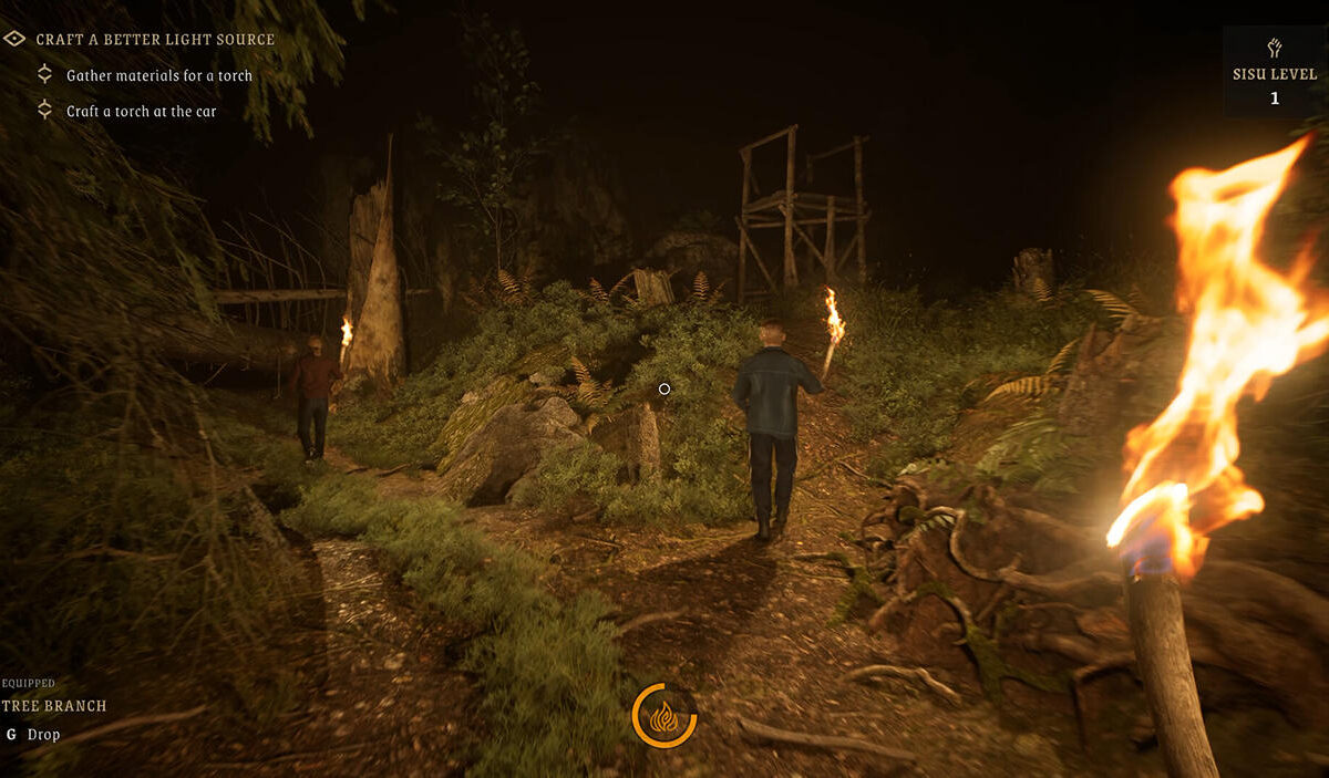 Gameplay-Screenshot aus RAHKO: Shadows Around Us: Zwei Spielfiguren laufen mit brennenden Fackeln durch einen dunklen Wald. Im Vordergrund ist die Fackel des Spielers zu sehen. Felsen, Büsche und ein hölzerner Hochstand liegen im schwachen Feuerschein.