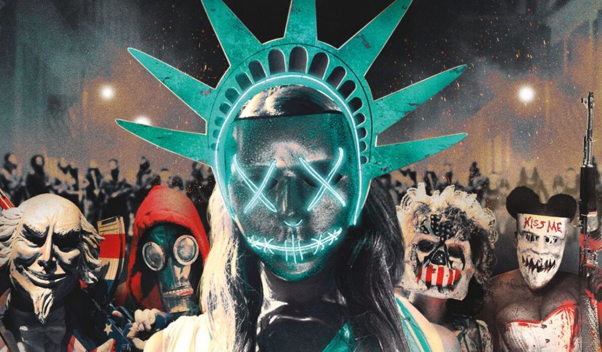 Maskierte Teilnehmer einer Purge-Nacht stehen vor einer Menschenmenge, im Zentrum eine leuchtende Freiheitsstatuen-Maske mit neonfarbenem Gesicht.