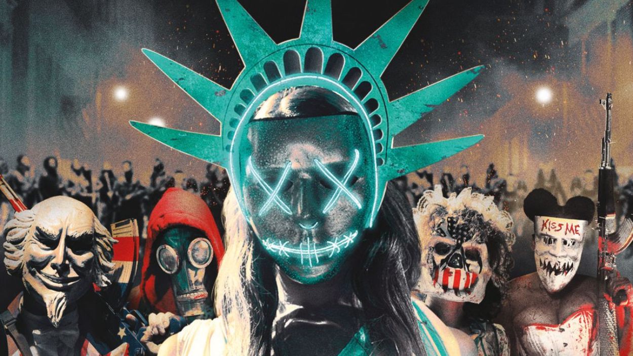 Maskierte Teilnehmer einer Purge-Nacht stehen vor einer Menschenmenge, im Zentrum eine leuchtende Freiheitsstatuen-Maske mit neonfarbenem Gesicht.