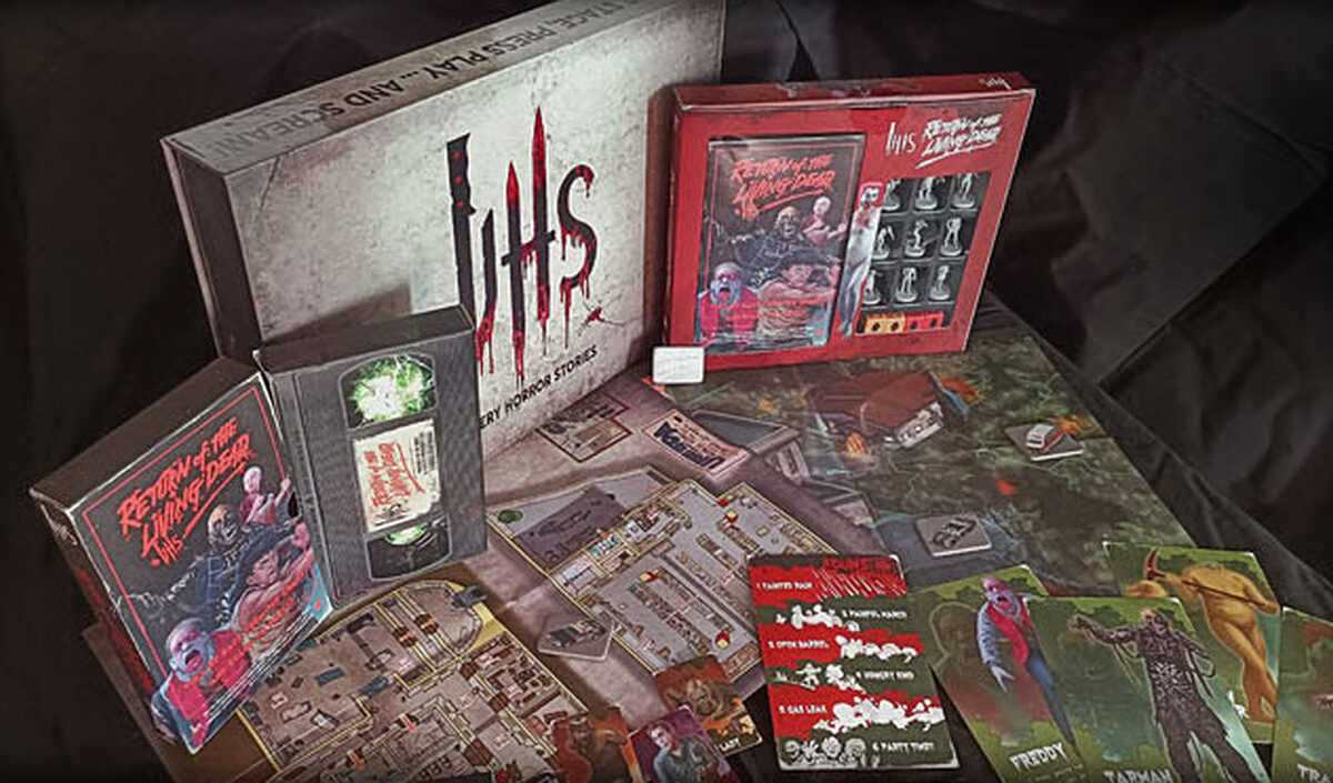 Produktaufnahme des Horror-Rollenspiels VHS: Return of the Living Dead von Aces Games. Zu sehen sind eine große VHS-Spielbox, eine rote Return-of-the-Living-Dead-Box sowie ausgebreitete Spielpläne, Regelhefte und farbige Charakter- und Monsterkarten.