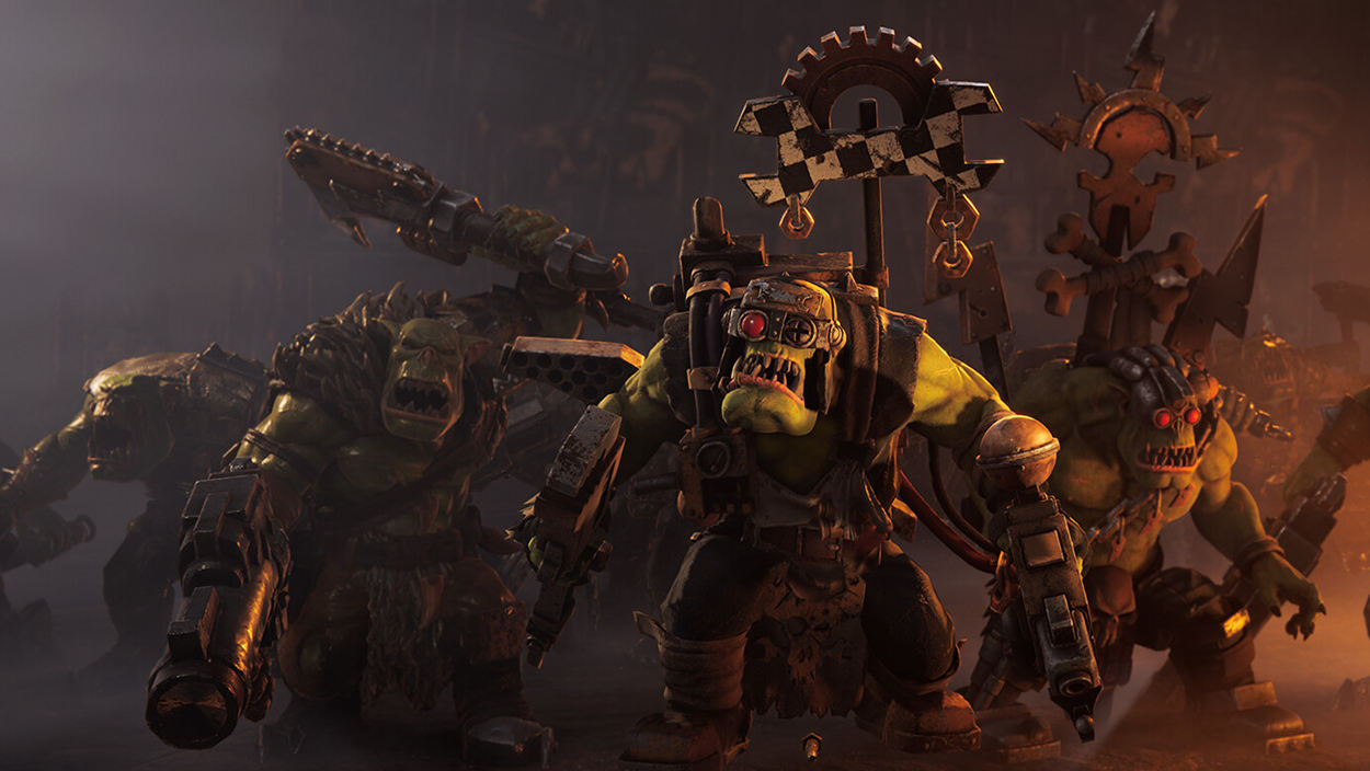 Mehrere bewaffnete Orks aus Warhammer 40.000: Dawn of War IV stürmen durch eine düstere, orange beleuchtete Kriegsszene. Im Vordergrund stehen schwer bewaffnete Grünhäute mit Metallrüstungen, Waffen und Ork-Bannern.